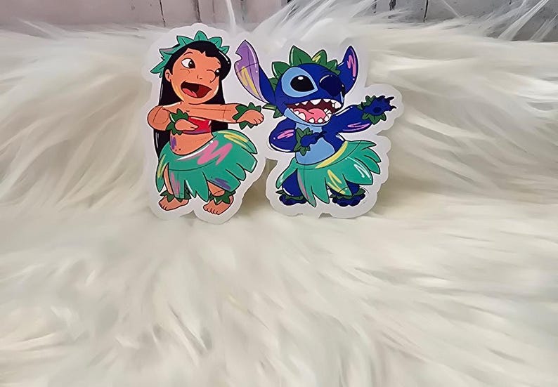 Puede incluir: Dos pegatinas con personajes de dibujos animados de la pel&iacute;cula de Disney Lilo & Stitch. La primera pegatina muestra a Lilo con una falda de hula y una flor en el pelo. La segunda pegatina muestra a Stitch con una falda de hula y un collar de flores alrededor del cuello.
