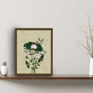 May include: A framed print of a watercolor painting of a pink lotus flower with green leaves on a beige background.