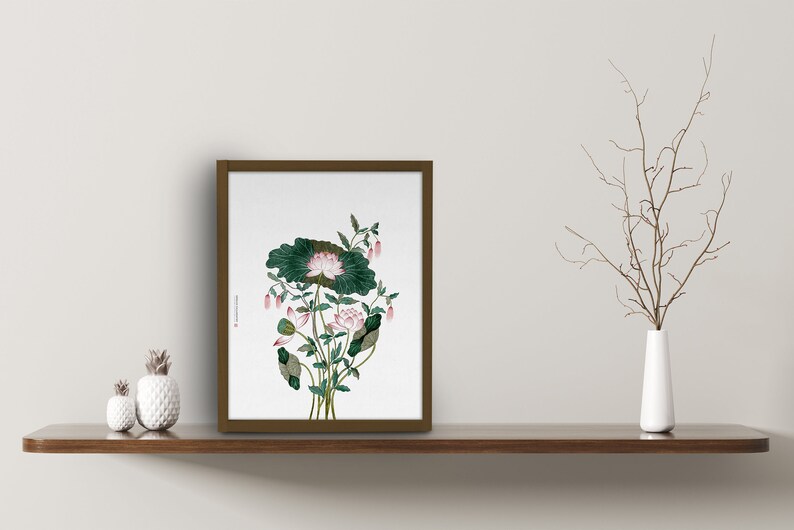 May include: A framed botanical print of a pink lotus flower with green leaves. The print is on a white background and has a brown frame.