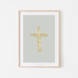 May include: A framed print with a light gray background and a yellow cross with the text "Abide in me" written vertically on the cross.