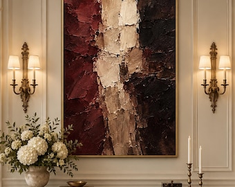 May include: A large rectangular abstract painting featuring thick, textured impasto layers in deep burgundy, metallic gold, and dark charcoal tones, framed in a thin gold border and displayed on a wall above a marble console table.