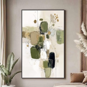 May include: Abstract art print featuring a composition of green, beige, black, and white shapes with gold accents. The artwork is framed in a black border and hangs on a neutral-toned wall, creating a modern aesthetic.