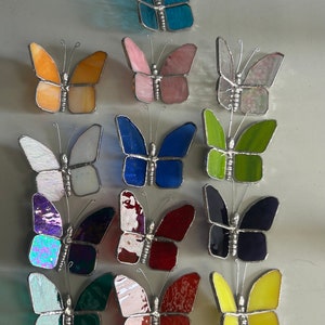 Pu&ograve; includere: Assortimento di 15 farfalle in vetro colorato in vari colori, tra cui blu, rosa, arancio, verde, viola, rosso, giallo e bianco. Le farfalle sono tutte di dimensioni approssimativamente uguali e hanno una cornice in filo d'argento.