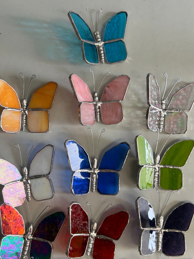 Pu&ograve; includere: Dodici ornamenti a forma di farfalla in vetro colorato, in vari colori, tra cui blu, rosa, arancio, bianco, verde, rosso e iridescente. Le farfalle sono tutte della stessa dimensione e forma, con una cornice in filo d'argento.