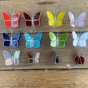 Pu&ograve; includere: Assortimento di farfalle e coccinelle in vetro colorato, in vari colori, tra cui rosso, blu, verde, giallo e rosa. Le farfalle sono di diverse dimensioni e forme, e alcune hanno accenti di glitter. Le coccinelle sono nere con macchie rosse.