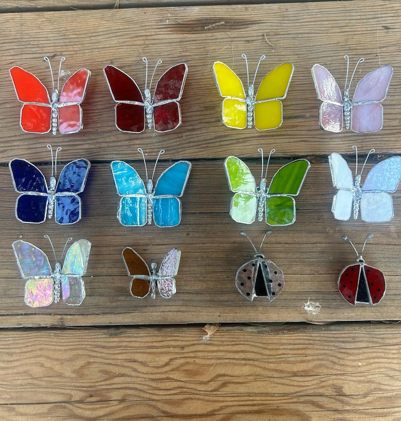 Pu&ograve; includere: Assortimento di farfalle e coccinelle in vetro colorato, in vari colori, tra cui rosso, blu, verde, giallo e rosa. Le farfalle sono di diverse dimensioni e forme, e alcune hanno accenti di glitter. Le coccinelle sono nere con macchie rosse.