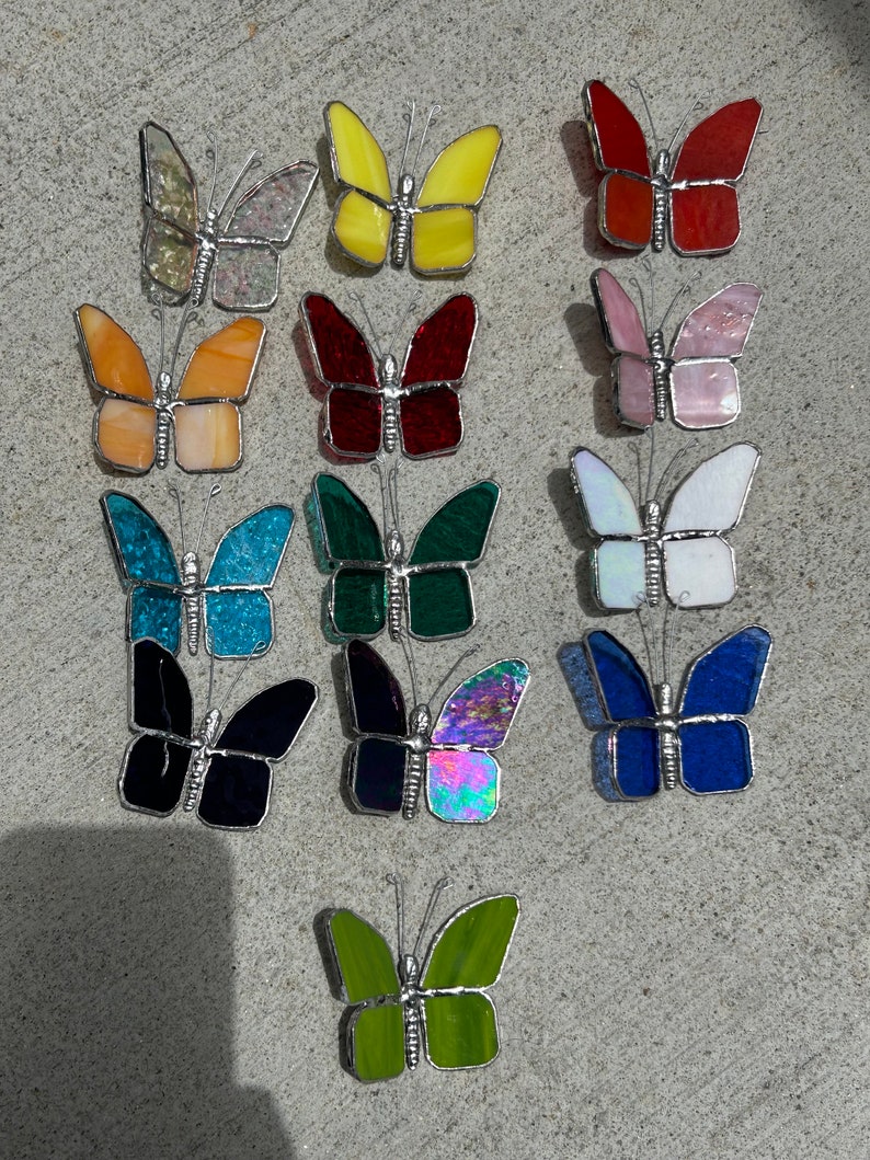 Pu&ograve; includere: Assortimento di 14 farfalle in vetro colorato in vari colori, tra cui giallo, rosso, rosa, blu, verde e iridescente. Ogni farfalla ha una cornice in metallo argentato e misura circa 5 cm.