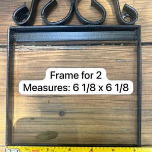 May include: Black metal frame with ornate scrollwork at the top. The frame measures 6 1/8 inches by 6 1/8 inches.