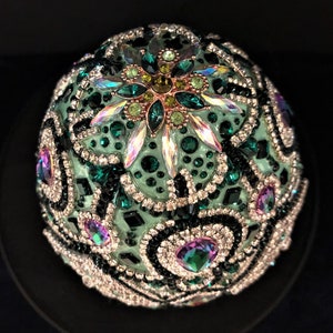 May include: A green, black and silver jeweled egg ornament with a large, iridescent crystal in the centre.
