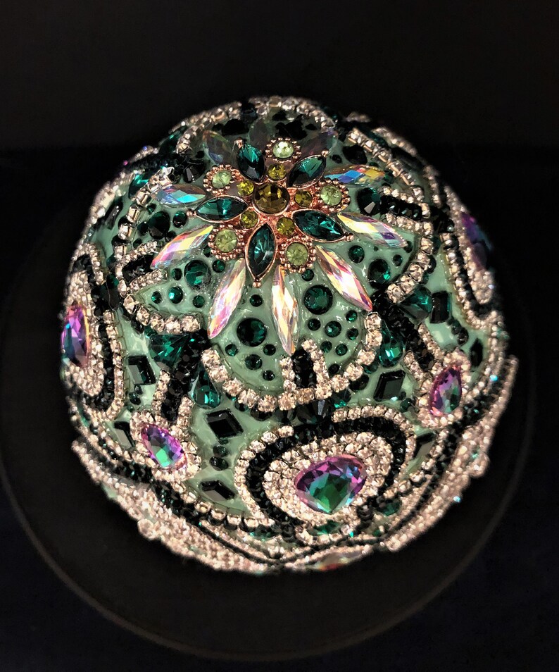 May include: A green, black and silver jeweled egg ornament with a large, iridescent crystal in the centre.