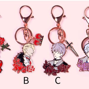 May include: Four different rose-themed keychains featuring anime characters. Each keychain has a gold-colored metal ring and a charm with a different character, including a pink-haired woman, a blonde man, a silver-haired man with a sword, and a silver-haired man with a rabbit mask.