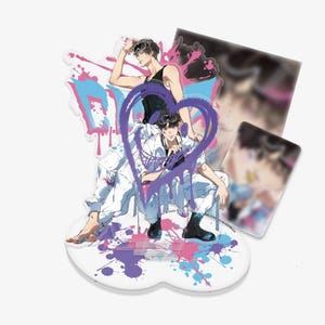 Puede incluir: Un soporte acrílico de estilo anime con dos figuras masculinas con trajes blancos, con un corazón morado y un diseño de salpicaduras de pintura. Incluye una tarjeta transparente con una imagen borrosa. La base es blanca con salpicaduras de pintura coloridas.