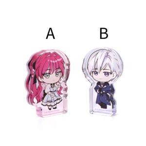 May include: Two acrylic anime character figures. One figure has pink hair and a white dress, the other has white hair and a dark blue outfit. Both figures are in a chibi style.