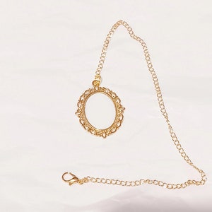 May include: A gold chain necklace with a decorative oval pendant. The pendant has a filigree design and is attached to the chain with a small loop.