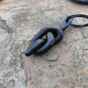 May include: Black metal keychain with a knot design and a silver key ring.
