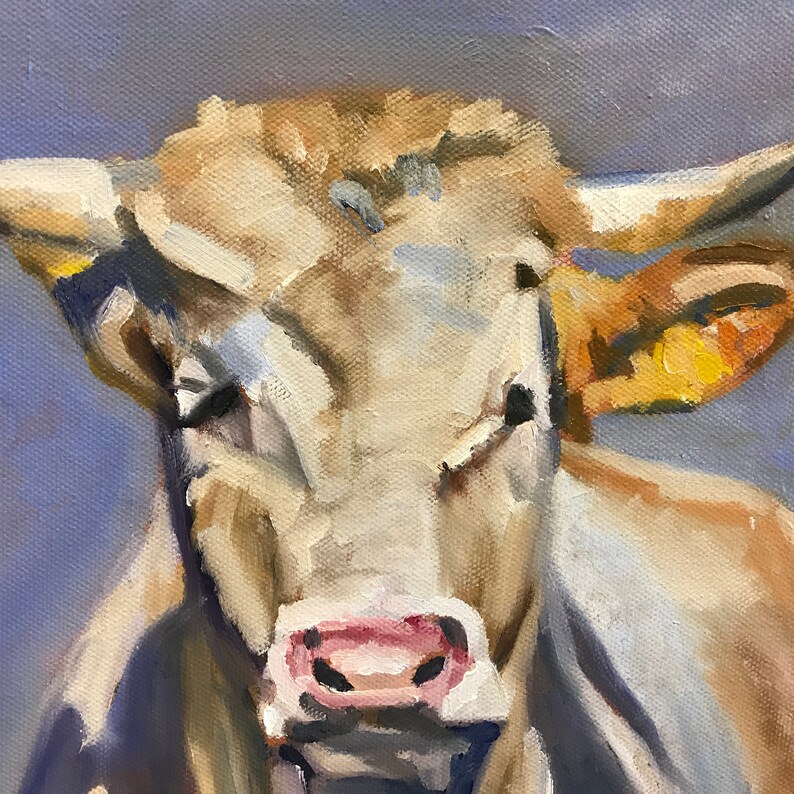 May include: A close-up portrait of a light brown cow with a pink nose and a yellow ear. The cow is looking directly at the viewer with a gentle expression.
