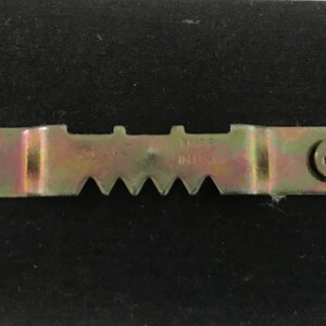 May include: A metal picture hanging hook with two screws. The hook has a serrated edge and the text "MADE IN U.S.A." is visible.