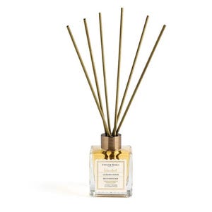 May include: A square glass reed diffuser with a gold-colored metal cap and a bundle of tan reeds. The liquid inside is amber-colored. The label reads "Istanbul Golden Hour Reed Diffuser".