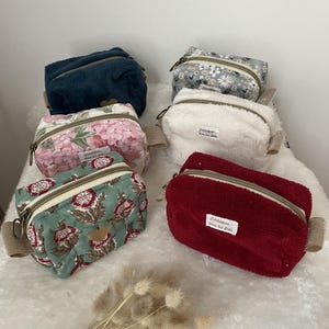 K&ouml;nnte beinhalten: Eine Sammlung kleiner Kosmetiktaschen mit Rei&szlig;verschluss in verschiedenen Farben und Mustern. Die Taschen umfassen einen dunkelblauen Pl&uuml;sch, einen Blumendruck, ein wei&szlig;es Frottee, ein rotes Frottee und einen Blumendruck mit gr&uuml;nem Hintergrund.
