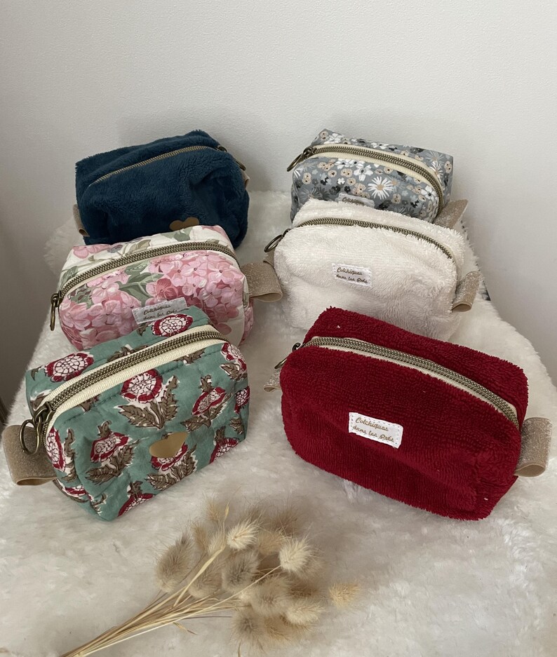 K&ouml;nnte beinhalten: Eine Sammlung kleiner Kosmetiktaschen mit Rei&szlig;verschluss in verschiedenen Farben und Mustern. Die Taschen umfassen einen dunkelblauen Pl&uuml;sch, einen Blumendruck, ein wei&szlig;es Frottee, ein rotes Frottee und einen Blumendruck mit gr&uuml;nem Hintergrund.