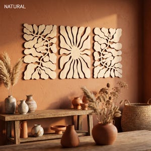 K&ouml;nnte beinhalten: Drei Wandpaneele aus Holz mit nat&uuml;rlicher Oberfl&auml;che, die abstrakte Blumendesigns zeigen. Die Paneele sind an einer terrakottafarbenen Wand angebracht. Eine Holzbank zeigt Vasen, Keramik und getrocknete Pflanzen. Das Wort "NATURAL" befindet sich oben links.