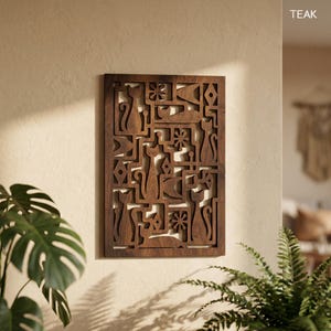 May include: A rectangular wooden wall art piece with a carved design featuring stylized cats, flowers, and geometric shapes. The artwork is a warm brown colour and is mounted on a light-coloured wall. The word "TEAK" is visible in the upper right corner.
