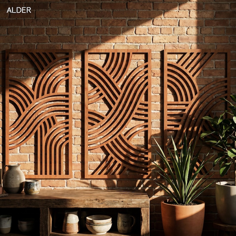 May include: Three wooden wall panels with a repeating wave-like design are mounted on a brick wall. The panels are a warm brown color and have a rectangular shape. The word "ALDER" is in the top left corner.