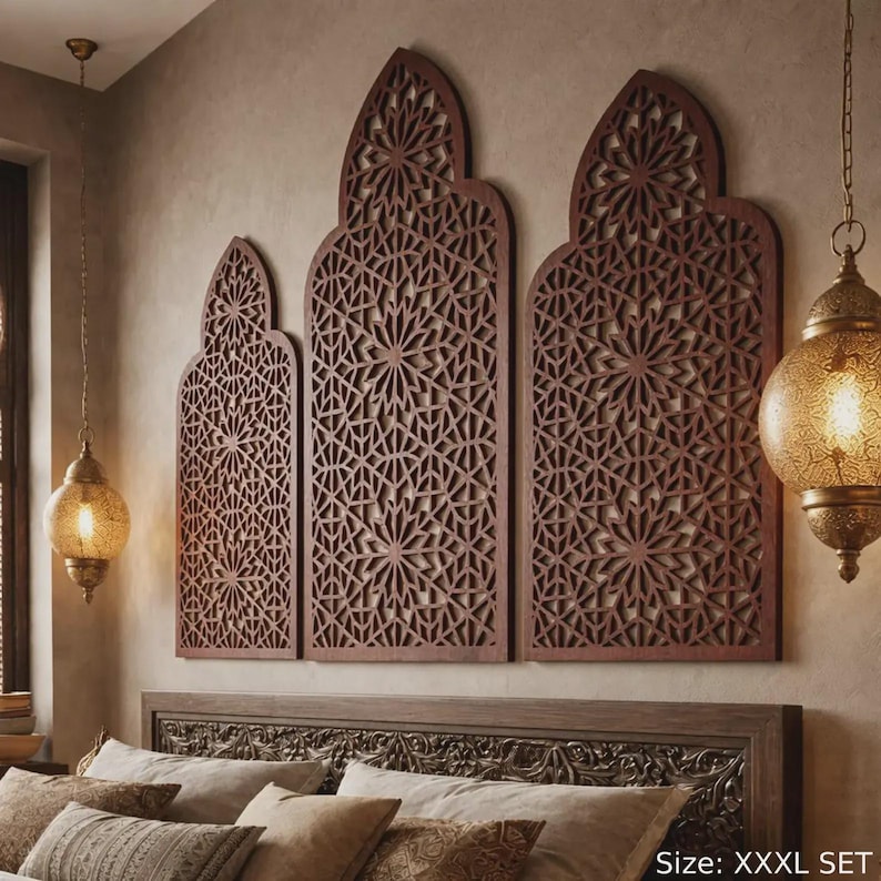 A luxurious bedroom featuring a wood accent wall with a triptych wall art display above the bed. The 3 piece wall art consists of large, arched accent wall panels carved from high-quality plywood. This moroccan wall panel set showcases intricate sacred geometry and moroccan lattice patterns resembling a moroccan door arch. Warm pendant lights illuminate the islamic wall art. Perfect as a moroccan wood panel installation or elegant ramadan decor, safely mounted with double-sided tape.