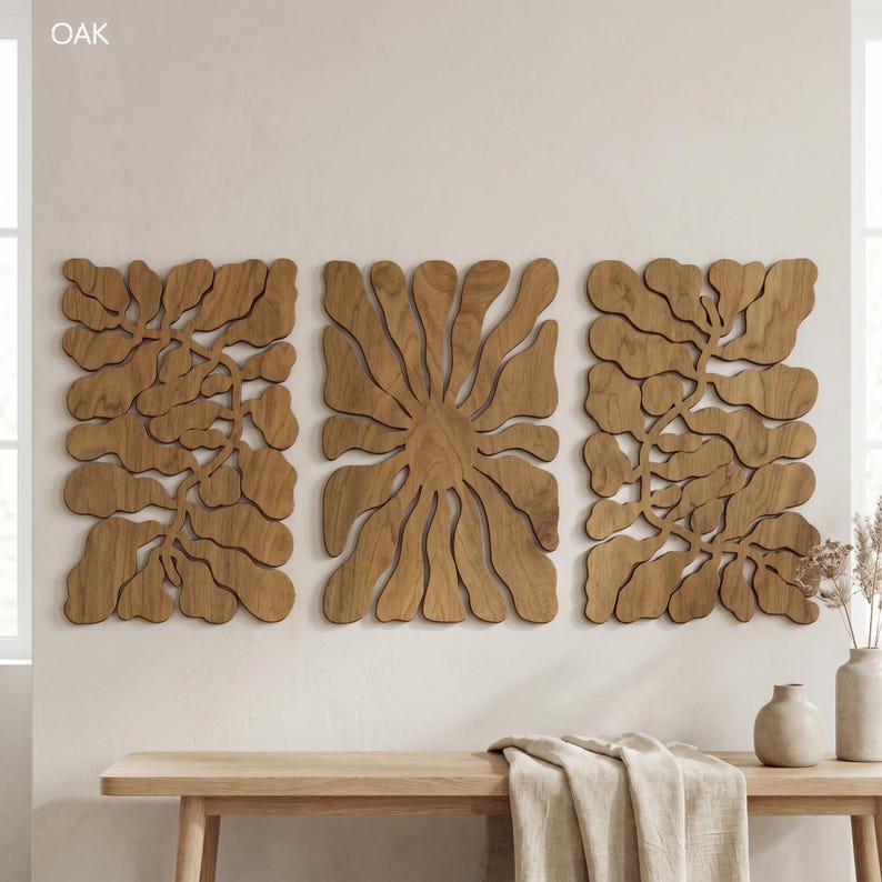 K&ouml;nnte beinhalten: Drei Wandpaneele aus Holz mit nat&uuml;rlicher Holzoberfl&auml;che. Die Paneele zeigen ein abstraktes Blumendesign, mit dem Wort "OAK" in der oberen linken Ecke. Die Paneele sind &uuml;ber einer Holzbank mit dekorativen Vasen und einem gefalteten Tuch angebracht.