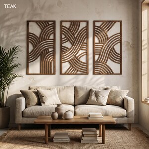 May include: Three rectangular wooden wall art panels with a repeating wave design. The panels are made of dark brown wood and are mounted on a light-colored wall. The word "TEAK" is in the upper left corner.