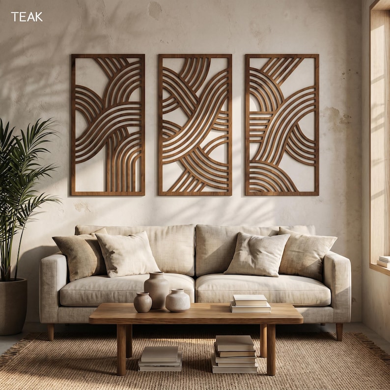 May include: Three rectangular wooden wall art panels with a repeating wave design. The panels are made of dark brown wood and are mounted on a light-colored wall. The word "TEAK" is in the upper left corner.