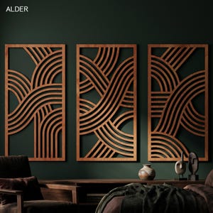 May include: Three wooden wall panels with a geometric design of curved lines. The panels are framed in a light brown color, with a dark brown design. The panels are mounted on a dark green wall.
