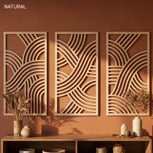 May include: Three wooden wall art panels with a geometric wave design. The panels are rectangular with a light wood finish, and the background is a warm, earthy tone. The word "NATURAL" is in the top left corner.