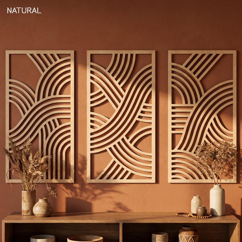 May include: Three wooden wall art panels with a geometric wave design. The panels are rectangular with a light wood finish, and the background is a warm, earthy tone. The word "NATURAL" is in the top left corner.