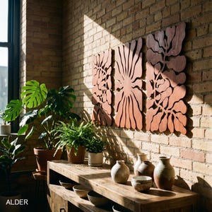 K&ouml;nnte beinhalten: Holzwandkunst mit floralem Design, an einer Backsteinmauer befestigt. Die Kunst hat einen warmen, r&ouml;tlich-braunen Farbton. Ein Holztisch zeigt verschiedene Keramikvasen und Schalen. Topfpflanzen sorgen f&uuml;r einen Hauch von Gr&uuml;n.