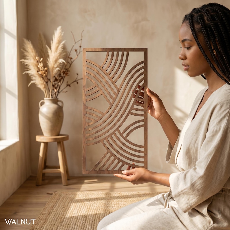 May include: A rectangular walnut wood wall art piece with a flowing, layered design. The artwork features curved lines and open spaces, creating a modern, abstract aesthetic. The word "WALNUT" is printed at the bottom.
