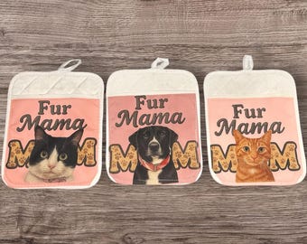 Puede incluir: Tres manoplas blancas y rosas con la inscripción "Fur Mama" y la cara de una mascota. Una tiene un gato blanco y negro, otra un perro negro y la última un gato naranja. Cada manopla tiene huellas de patas.