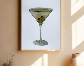 May include: A framed watercolor print of a martini cocktail. The drink is in a classic glass with two green olives. The artwork is displayed on a light-colored wall, with a wooden frame.