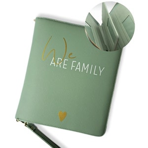 Könnte beinhalten: Eine salbeigrüne Reißverschlusstasche mit einem goldenen Herzen und dem Text "We Are Family" in goldenen Buchstaben.