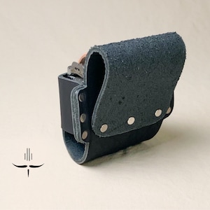 Puede incluir: Un portaherramientas de cuero negro con un clip de metal y remaches. El portaherramientas est&aacute; dise&ntilde;ado para llevarse en un cintur&oacute;n.