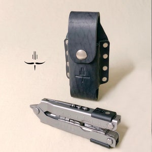 May include: A black leather multi-tool pouch with a silver snap closure and a silver logo. A silver multi-tool with a black handle is shown next to the pouch.