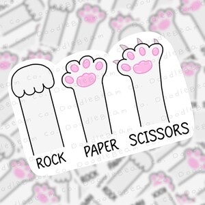 May include: A set of three white paw print stickers with pink accents. The stickers are labelled "ROCK", "PAPER", and "SCISSORS".