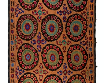 Könnte beinhalten: Ein großes, rechteckiges, besticktes Textil mit einem sich wiederholenden Muster aus konzentrischen Kreisen in Orange-, Grün-, Blau-, Rot- und Schwarztönen. Das Textil hat einen schwarzen Rand mit einem sich wiederholenden Muster aus kleinen Blumen.