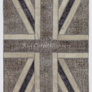 Peut inclure: Un tapis en patchwork avec un motif Union Jack dans des tons de gris et beige. Le tapis est fait de matériaux recyclés et a un aspect vieilli.