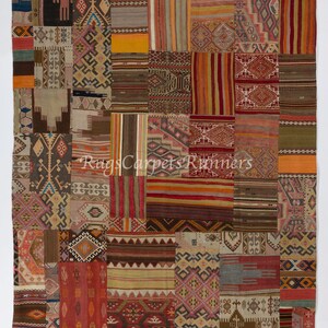 Könnte beinhalten: Ein Patchwork-Teppich mit verschiedenen geometrischen Mustern in Rot-, Braun-, Beige- und Blautönen. Der Teppich besteht aus vielen kleineren Stoffstücken, die zusammengenäht wurden.
