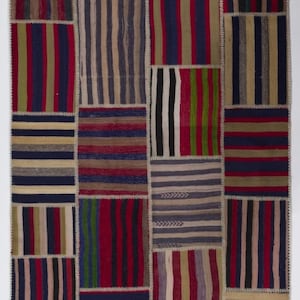 May include: A patchwork rug made from various strips of fabric in shades of red, blue, green, brown, and beige. The rug is made up of many different sized squares and rectangles, all sewn together to create a unique and colorful design.