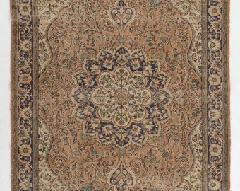 May include: A vintage Persian rug with a beige background and intricate floral patterns in shades of brown, blue, and green. The rug has a central medallion with a starburst design and a border with a repeating floral motif.