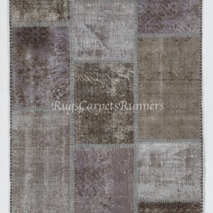 May include: A patchwork rug with a variety of shades of brown and gray. The rug is made of different pieces of fabric that have been sewn together. The rug has a distressed look and is perfect for adding a touch of rustic charm to any room.