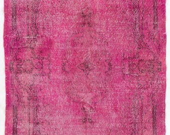 Könnte beinhalten: Ein rechteckiger Teppich mit einer leuchtend pinken Grundfarbe und komplexen, verblassten schwarzen Linienmustern. Das Design umfasst ein zentrales Medaillon, umgeben von verzierten Blumenmotiven und einer detaillierten Bordüre im Used-Look.