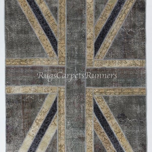 May include: A patchwork rug with a Union Jack design. The rug is made of different fabrics in shades of gray, beige, and black. The rug is a vintage style and has a distressed look.